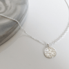 shiny silver coin with stars and dots on it set against a white and gray marble