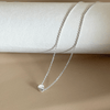 charm necklace with a tiny silver dot set against a natural background