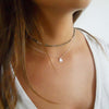 a beaded choker and a medallion coin necklace styled together on a woman 