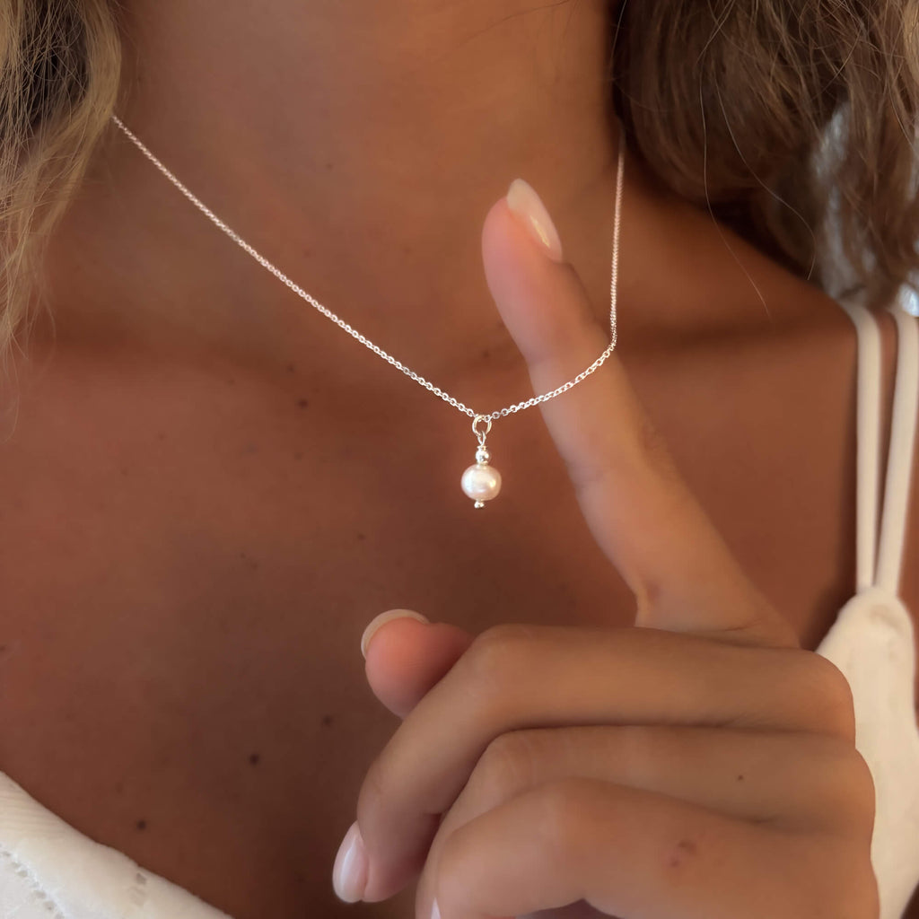 women wearing a necklace made with a dainty sterling silver chain and a freswater round pearl 