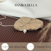 Silver necklace with pearl pendant on a rock, featuring 'AnniKA BELLA' branding.