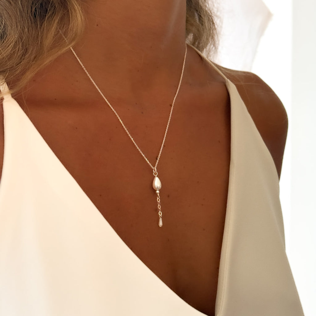 Y Necklace with a pearl pendant worn by a woman in a white top.