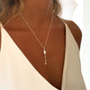 Y Necklace with a pearl pendant worn by a woman in a white top.