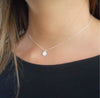 sparkly silver chain with a charm coin on a model 