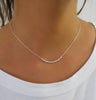 a simple minimalist silver necklace on a woman