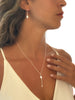 Close-up of a woman wearing a delicate lariat necklace with a pendant.