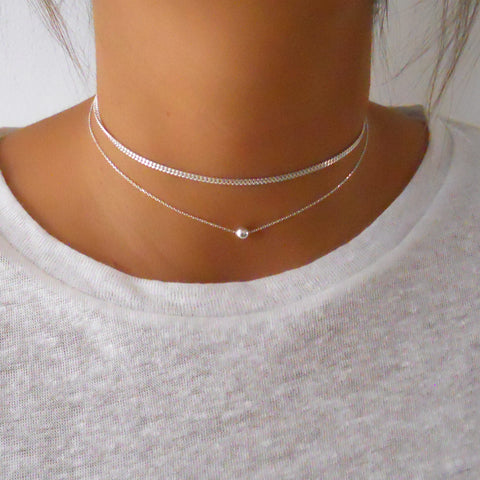 woman wearing two stacked necklaces - a gourmet chain and a ball choker 