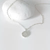 a silver neck chain with a disc charm paved by cubic zirconia stones in the shape of a north star